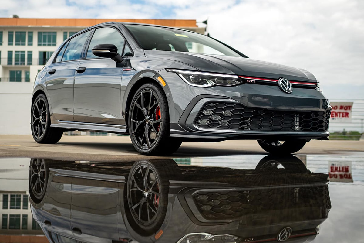 A Volkswagen GTI parked with its reflection showing in a puddle