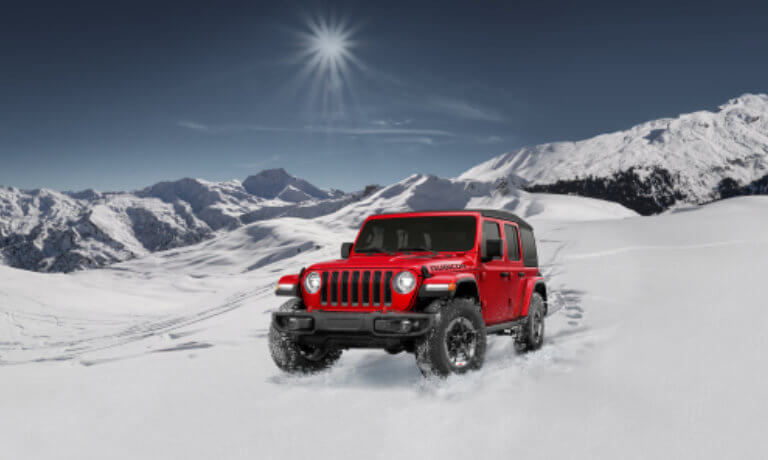 2021 Jeep Wrangler exterior on a road near snowy mountains