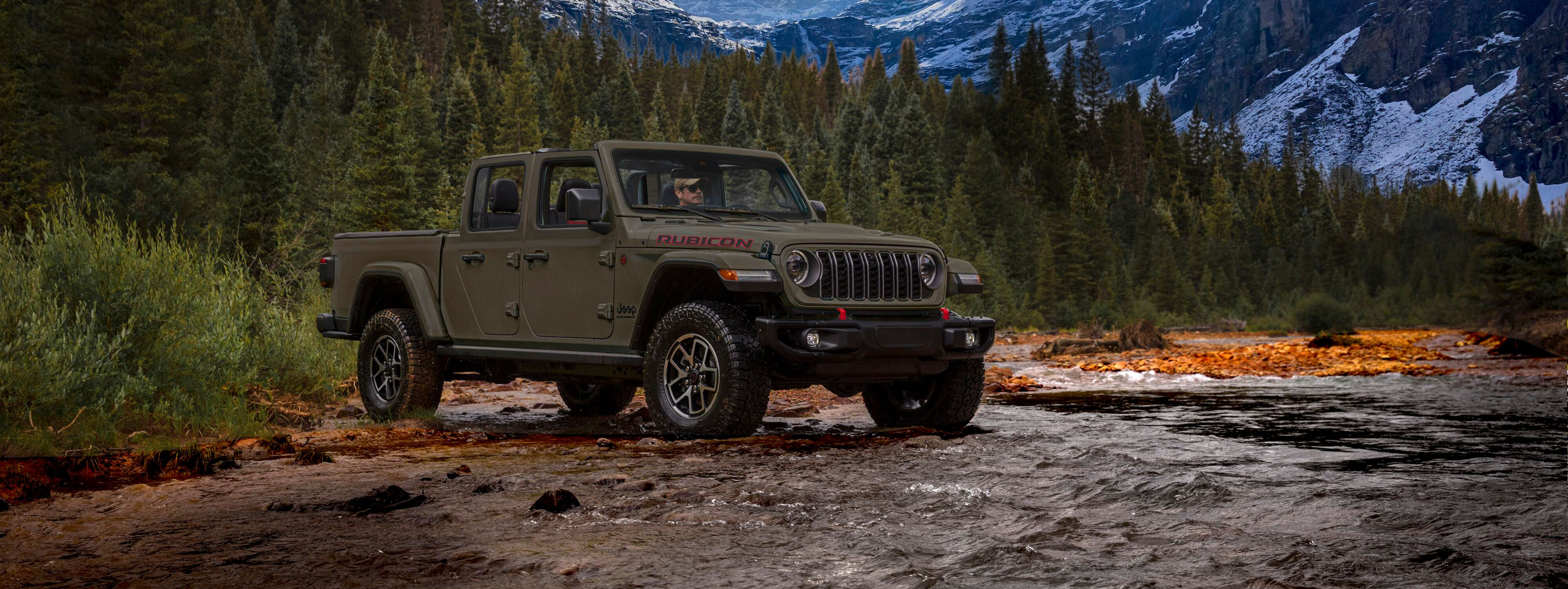 2027 Jeep Cherokee Jeep Gladiator Rubicon pickup truck driving through a shallow stream in a mountains