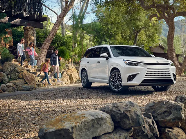 A Lexus TX sits in a forested area