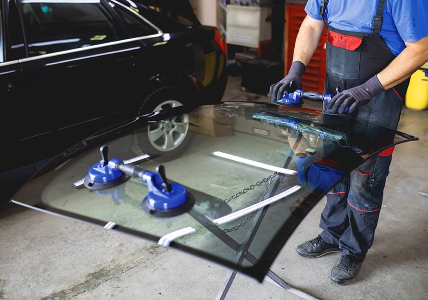 A worker preps a windshield for replacement