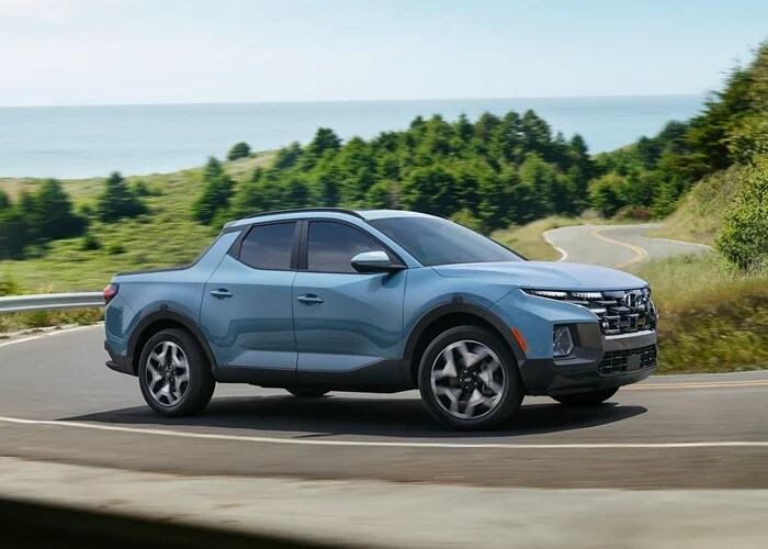 Powder blue 2023 Hyundai Santa Cruz driving on a winding road