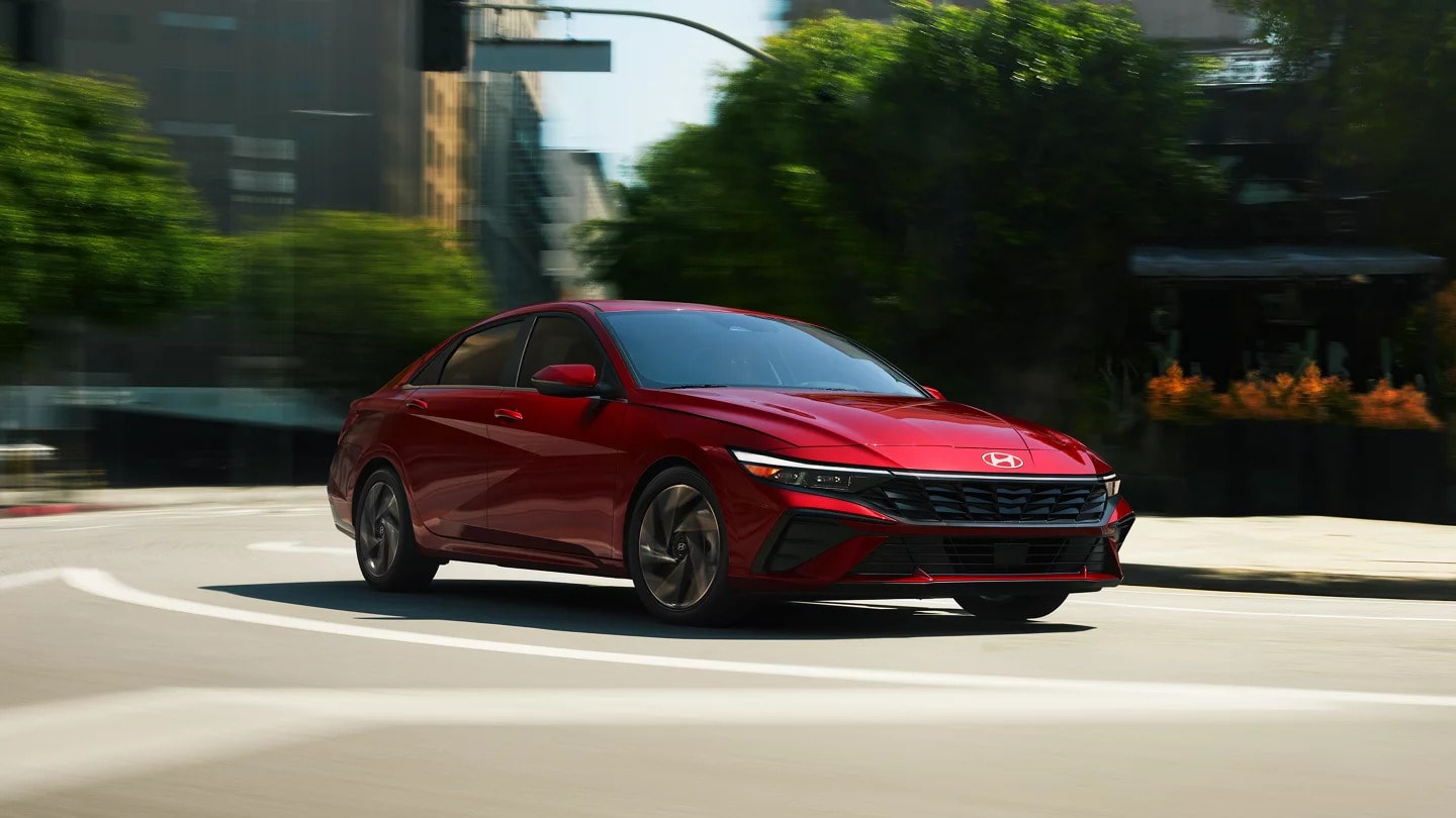 A red 2025 Hyundai Elantra quickly driving around a corner