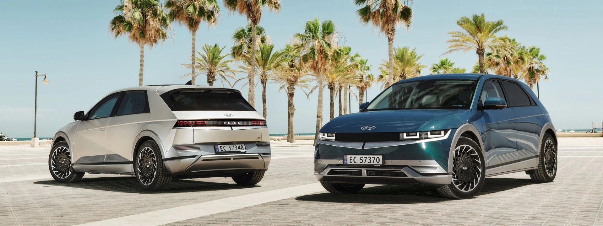 Two Hyundai Ioniq 5 models with a clear sky and trees in the background