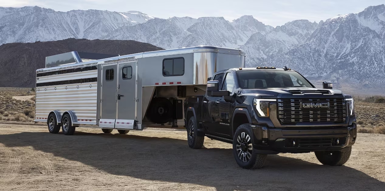 2024 GMC Sierra towing a trailer on a dirt road
