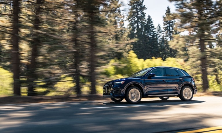 2021 Audi Q5 exterior blue driving in forest along trees.jpg