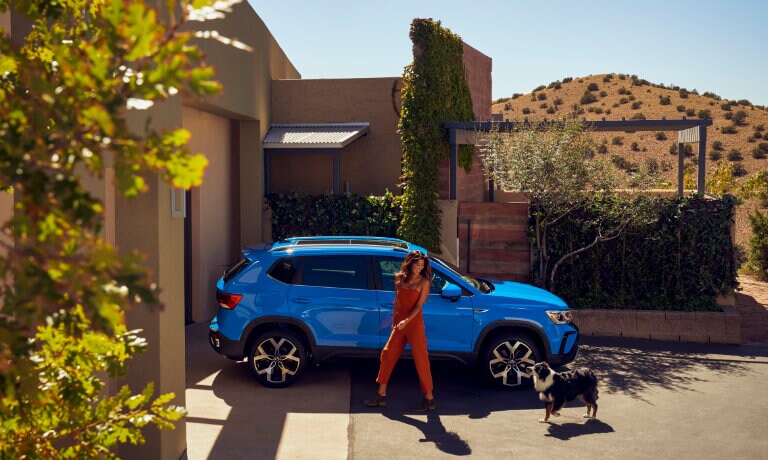 2022 Volkswagen Taos parked on a driveway with woman and dog