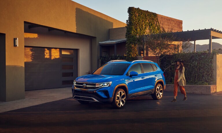 2022 Volkswagen Taos parked on a driveway at sunset with woman