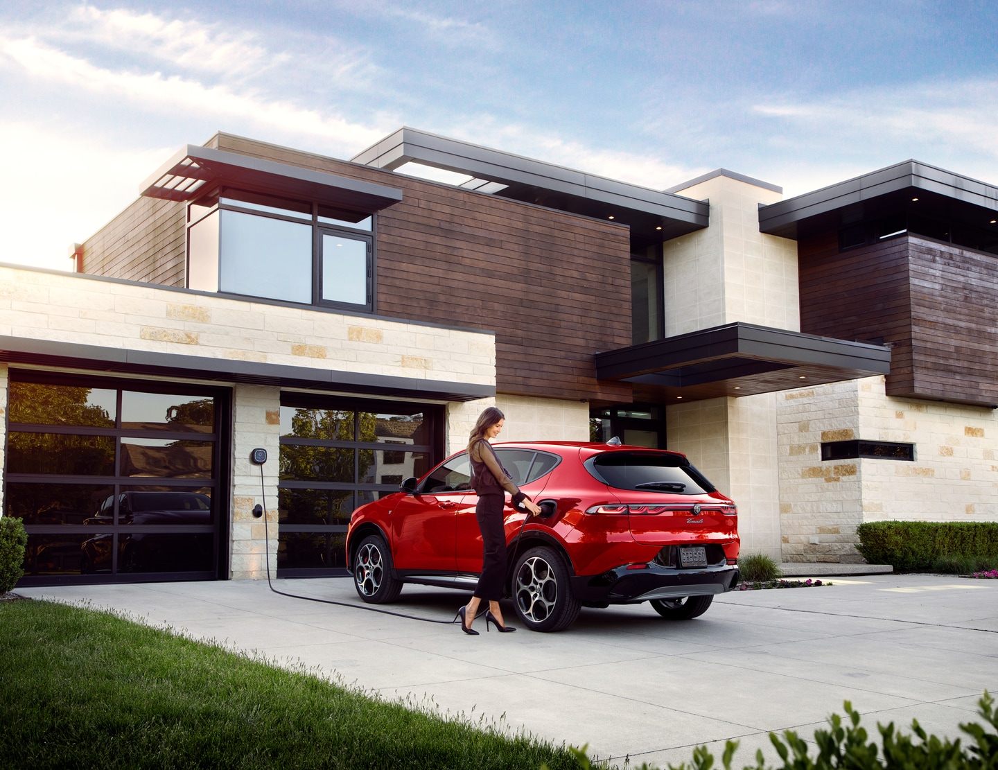  Woman plugging in a 2025 Alfa Romeo Tonale Ti in driveway