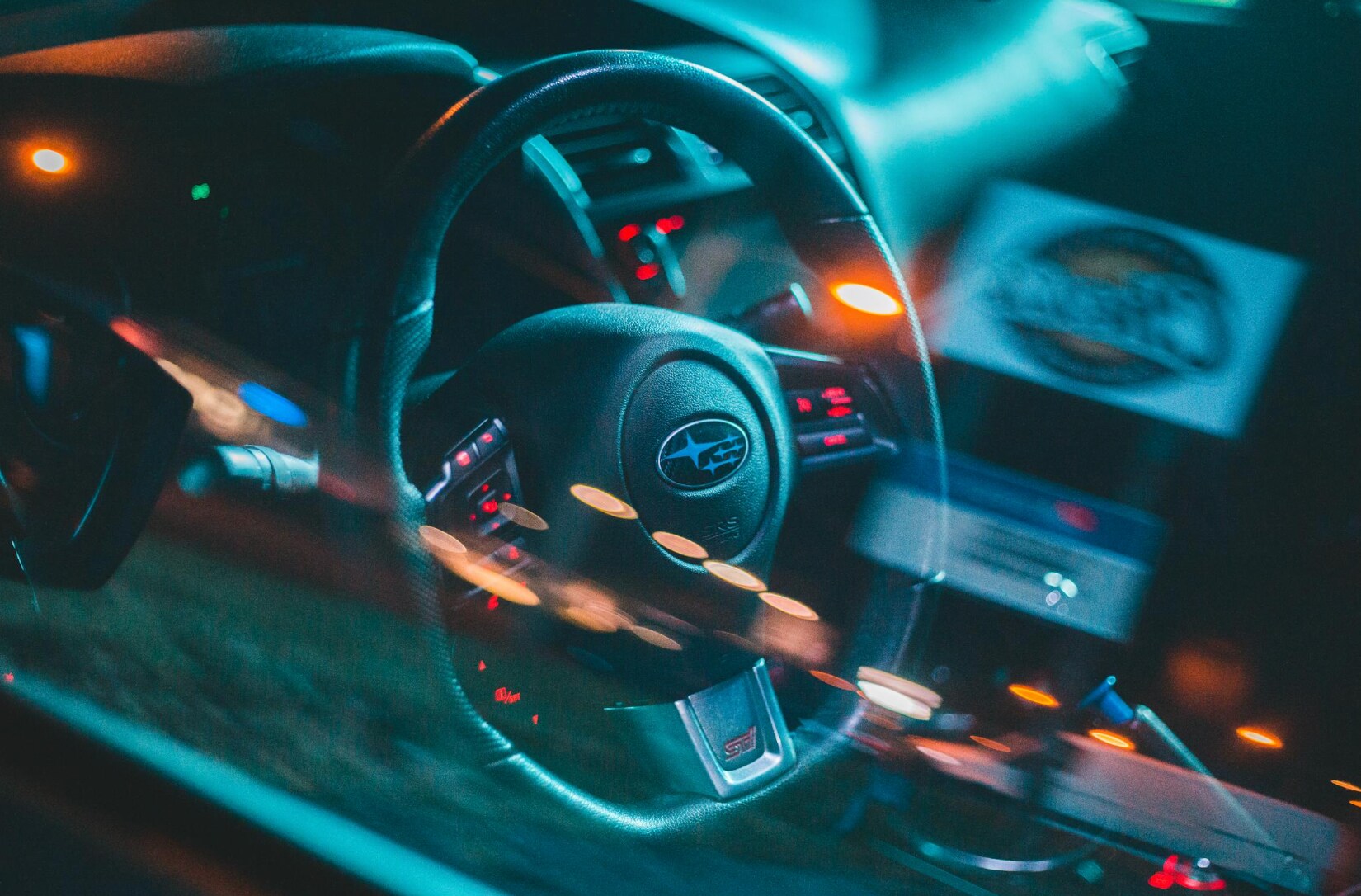 a subaru steering wheel with street lights reflection in the window a subaru steering wheel with street lights reflection in the window