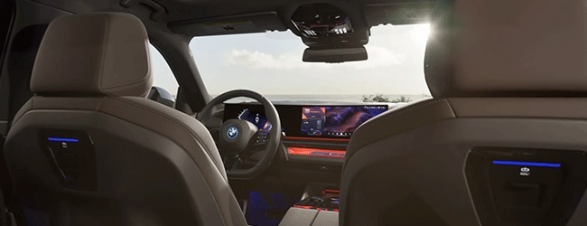 2025 BMW i5 interior with curved display and ambient lighting, seen from back seat