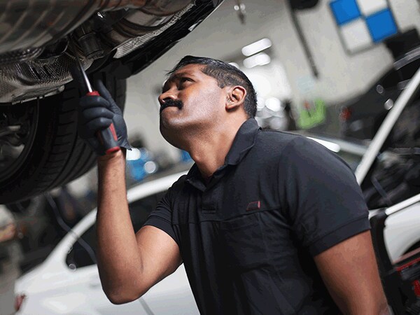 BMW technician inspecting undercarriage during service at Thompson BMW in Doylestown, PA