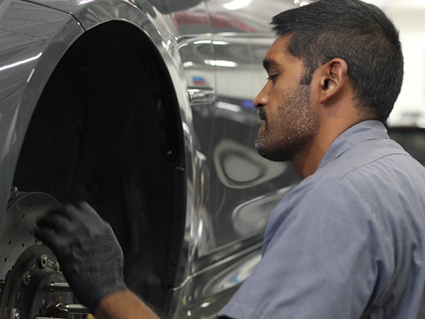 Technician performing brake maintenance on a BMW vehicle inside the service center