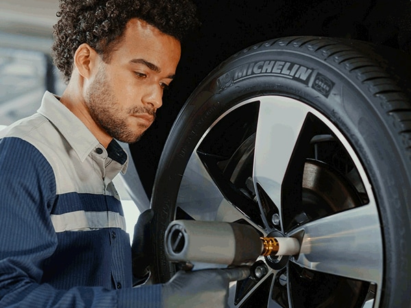 BMW technician tightening lug nuts on a Michelin tire with a power tool during service inspection