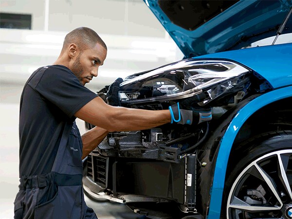 BMW technician replacing front headlight on blue SUV at Thompson BMW in Doylestown, PA