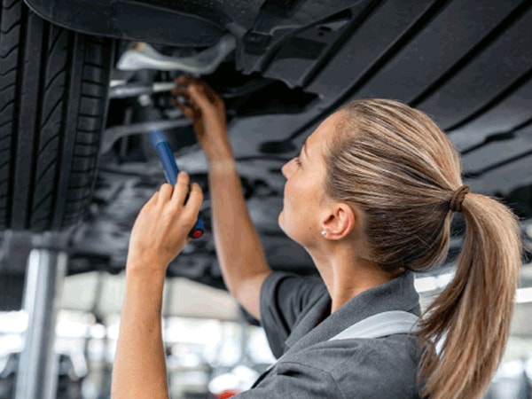 BMW technician inspecting suspension components beneath a lifted vehicle