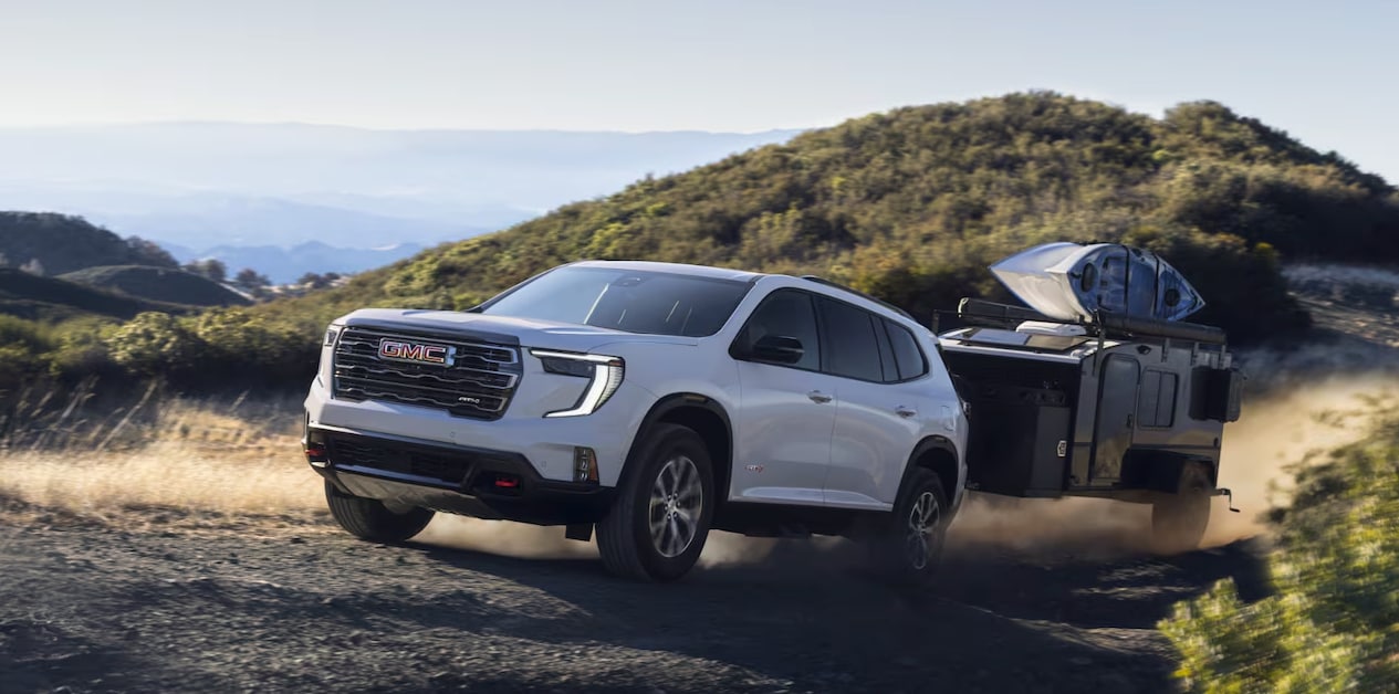2024 GMC Acadia towing on a trailer on a dirt road
