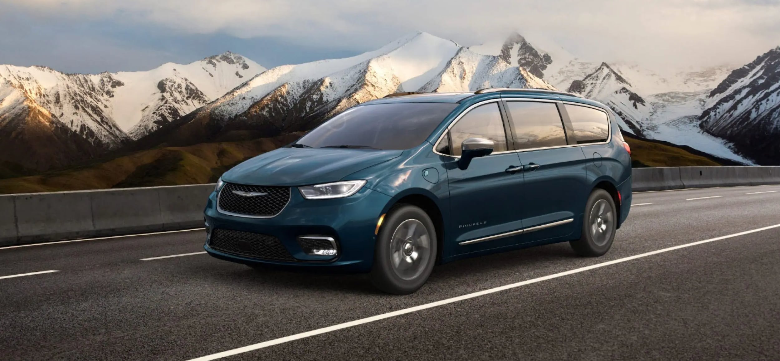 2023 Chrysler Pacifica Hybrid driving by snowy mountains