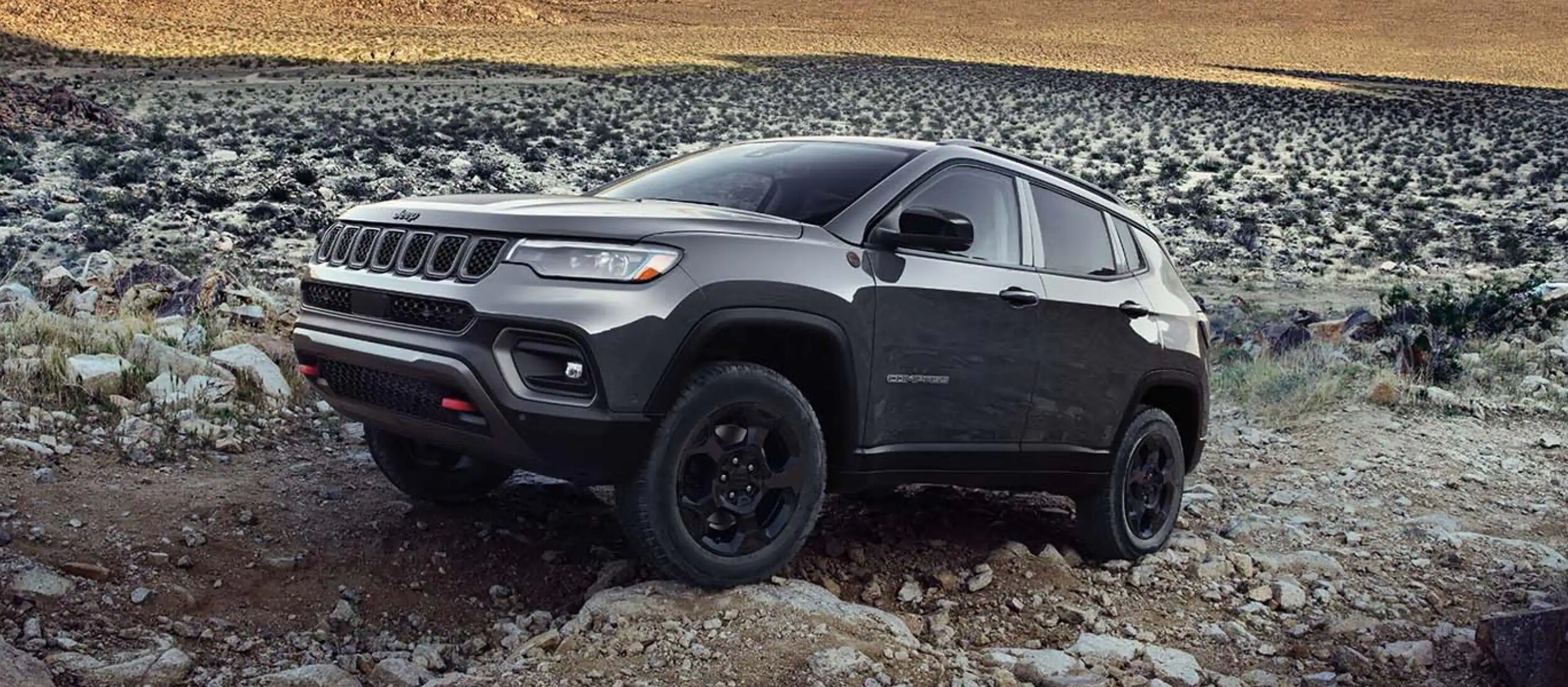 2023 silver Jeep Compass going over rocks