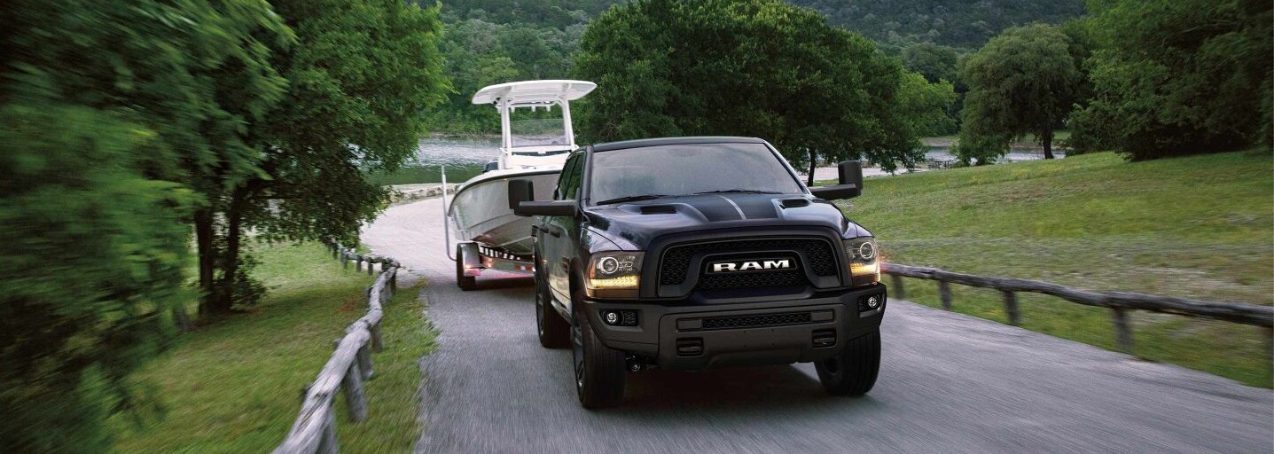 Front view of the 2022 RAM 1500 towing a boat with a body of water behind it