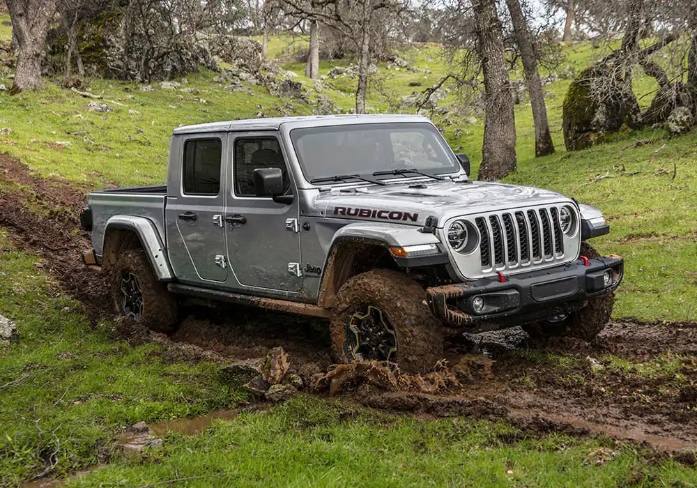 Grey 2023 Jeep Gladiator driving thorough the mud