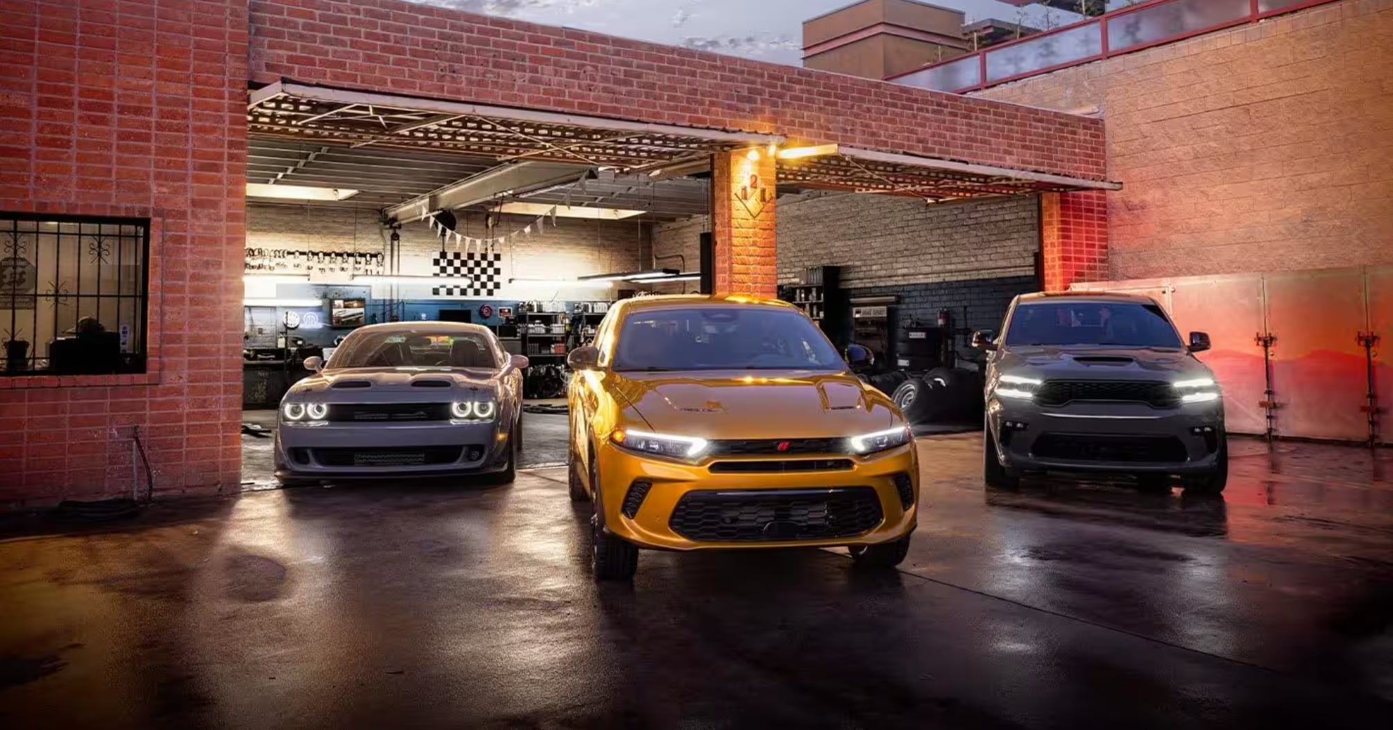 Three 2024 Dodge Hornet models in front of an auto body shop