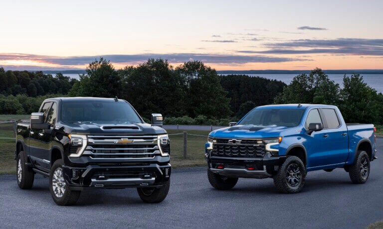 Two 2025 Chevy Silverado 2500 HDs parked overlooking a lake
