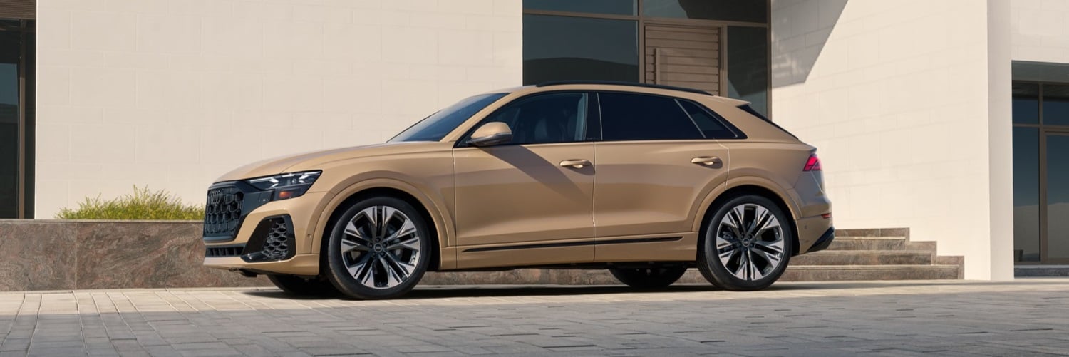 Gold Q8 Premium Plus parked by a modern house