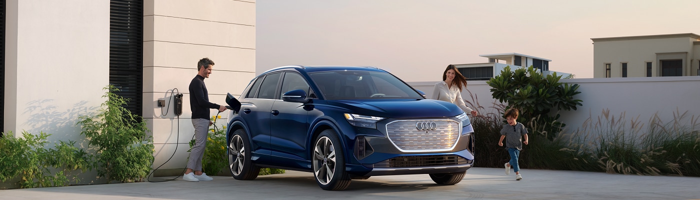 Audi Q4 e-tron being plugged in by a family