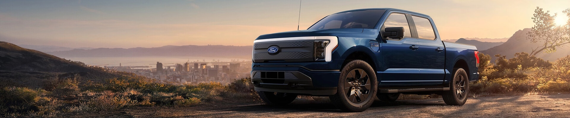 Blue Ford F-150 Lightning electric pickup truck at sunset