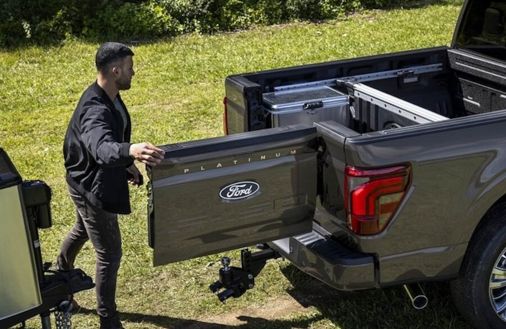 Two people exiting a 2025 Ford F-150® XLT pickup in Rapid Red hitched to a trailer of ATVs
