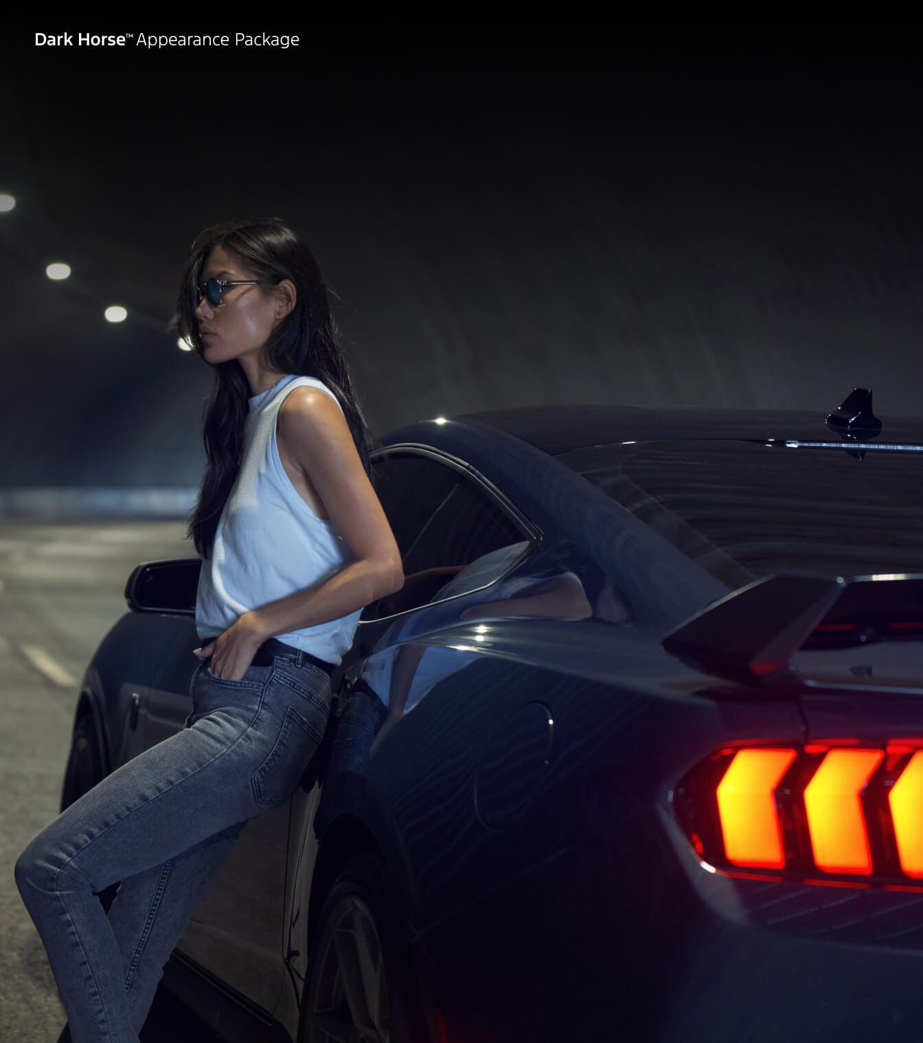 Woman leaning on Ford Mustand Dark Horse with Appearance Package at night