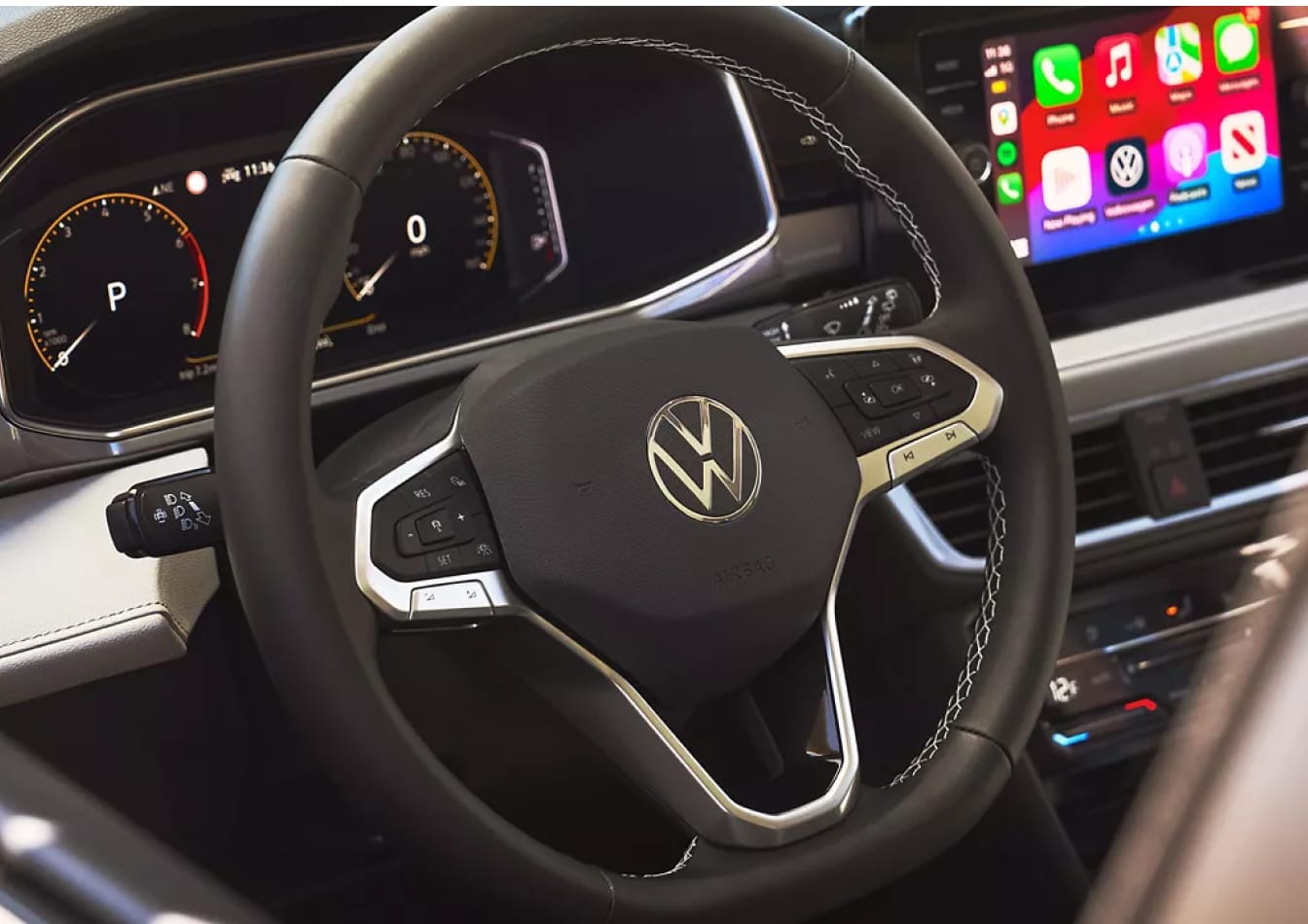 Close-up of a Volkswagen steering wheel with a digital instrument cluster and infotainment screen displaying Apple CarPlay.
