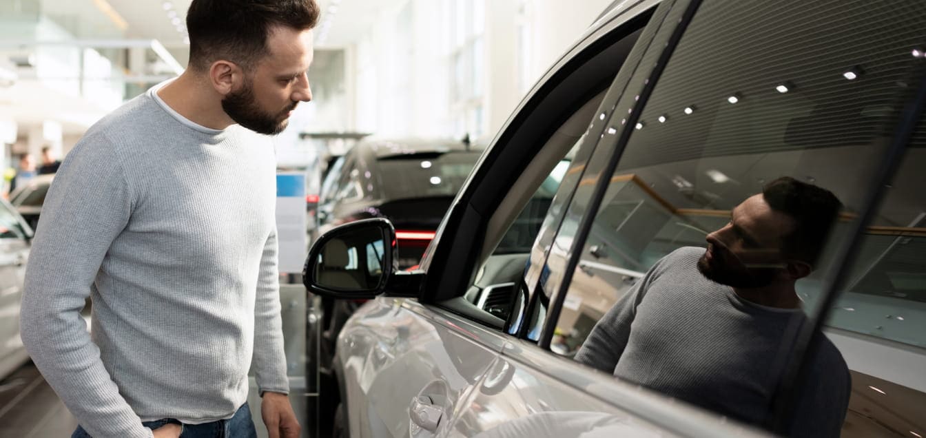 Customer inspecting a vehicle inside a dealership showroom.