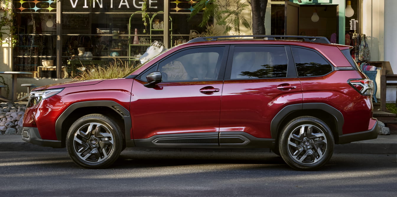 Red Subaru Forester shown in side profile parked on a city street in front of storefronts.