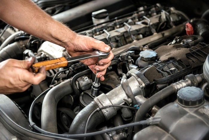 Mechanic_Using_Wrench_And_Socket_Under_Car_Hood.jpg