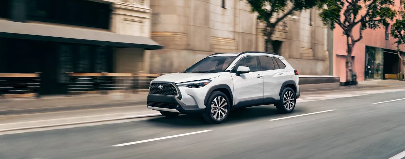 A white 2023 Toyota Corolla Cross XLE is driving on a city street.