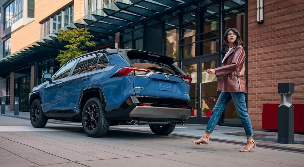 Woman walking near a blue 2023 Toyota RAV4