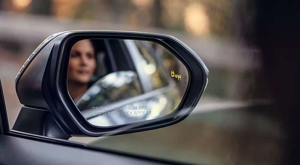 Person reflecting in the side mirror on a white 2026 Toyota Corolla
