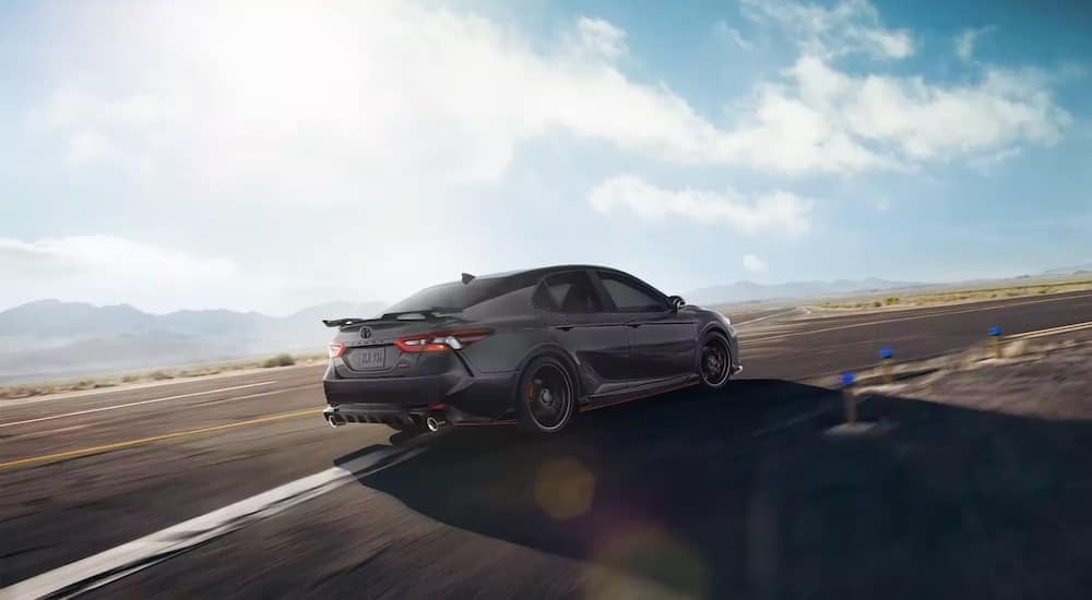 Rear view of a black 2022 Toyota Camry TRD driving on a racetrack.
