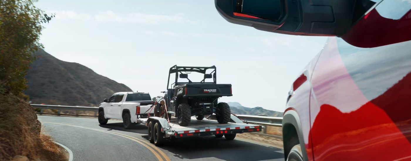 A white 2024 Toyota Tundra for sale is shown towing an ATV.