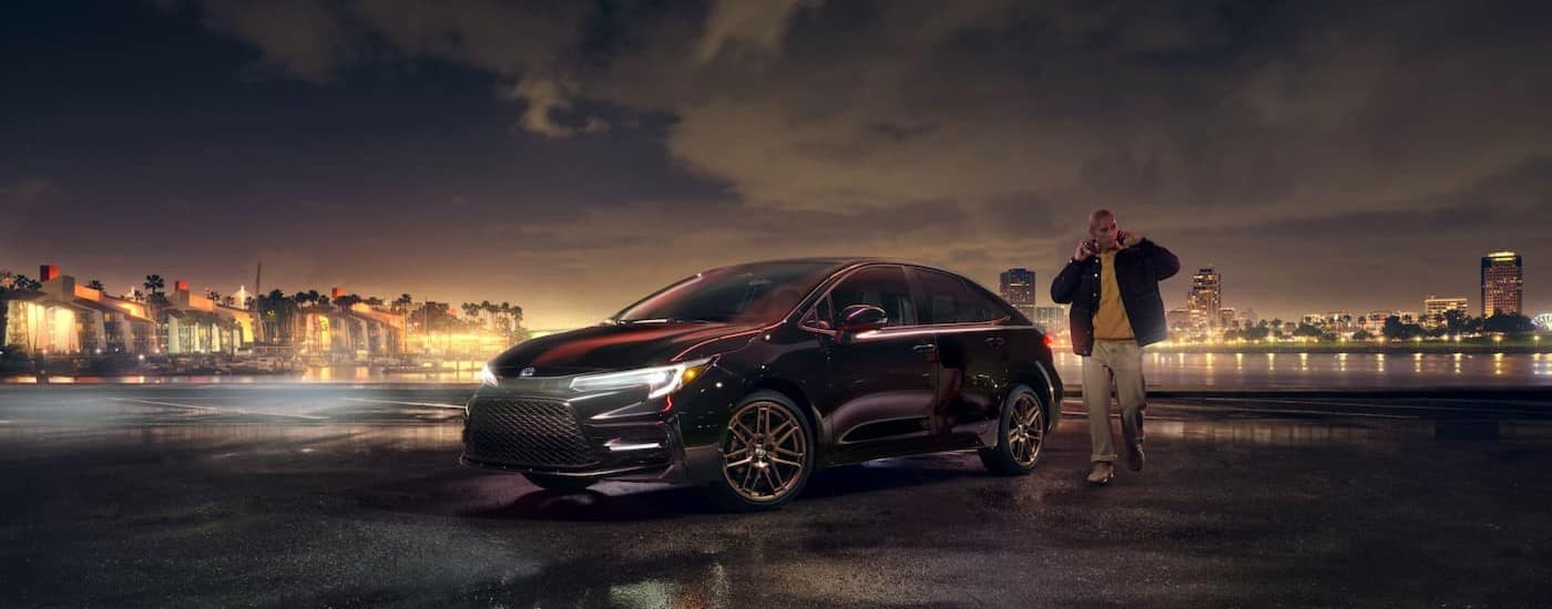 A black 2024 Toyota Corolla parked at night with its lights on.