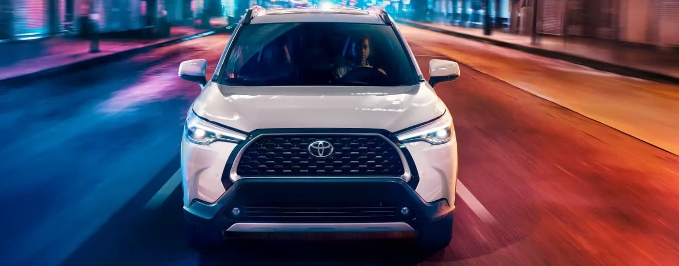 A white 2023 used Toyota Corolla Cross for sale in Hopkinsville driving on a city street.