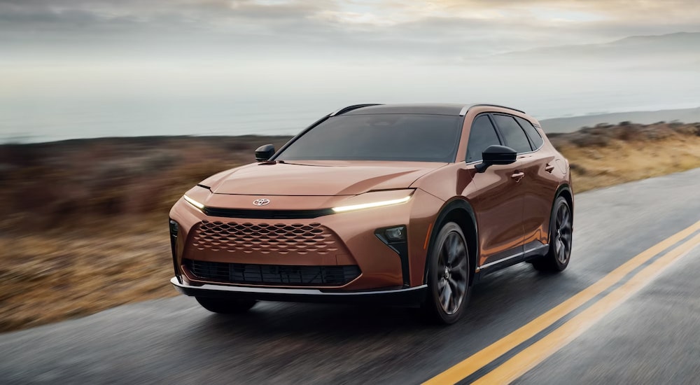 A bronze-colored 2025 Toyota Crown Signia Limited driving along a coastal road.