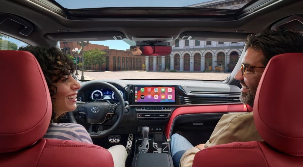 Smiling people are shown sitting in a 2025 Toyota Camry XSE.