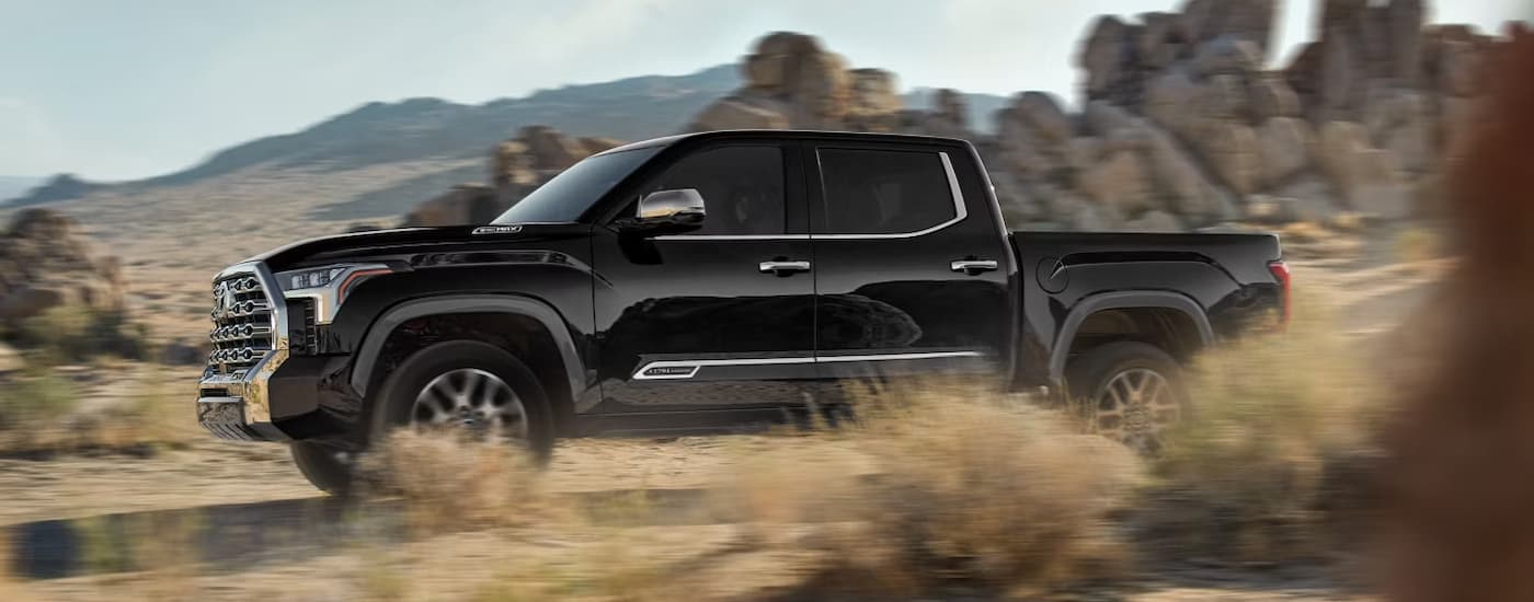 Side of a black 2026 Toyota Tundra driving on sand