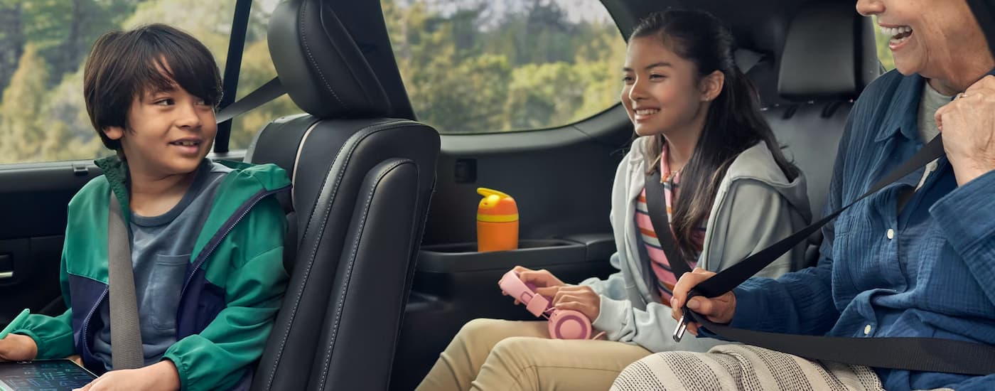 Two children and a woman are sitting in the rear seats of a 2025 Toyota Grand Highlander.