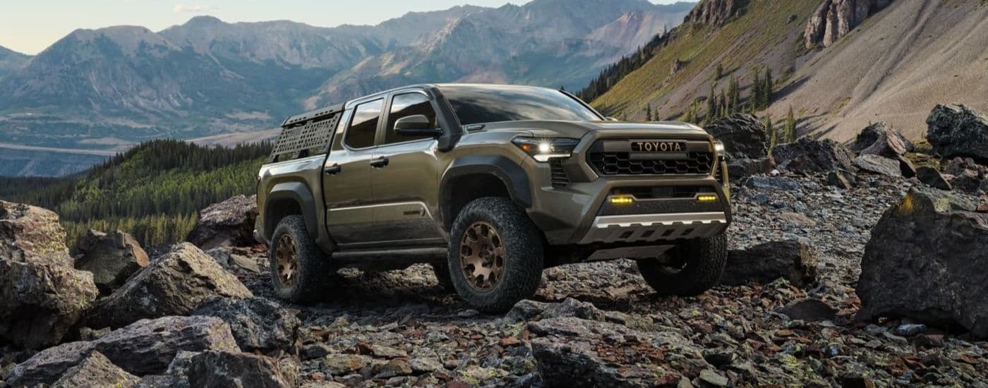 A green 2024 Toyota Tacoma Trailhunter is shown off-road after leaving a Toyota dealer.