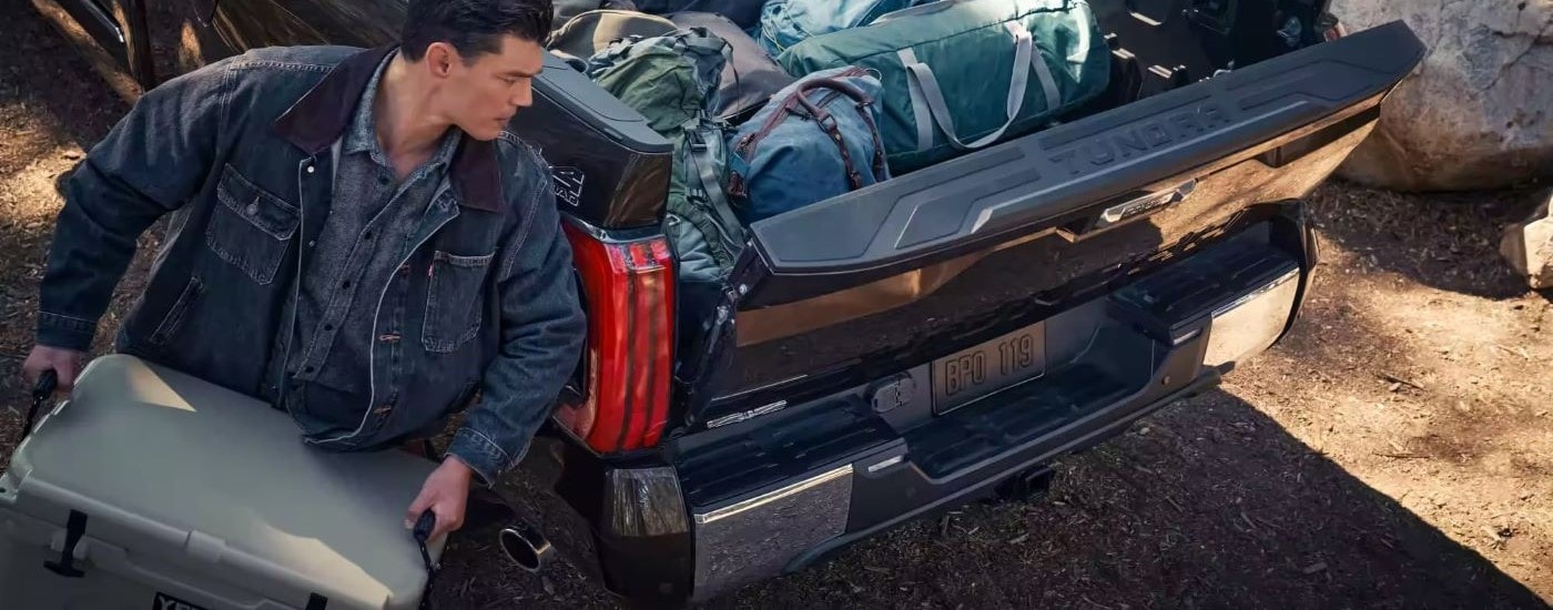 Man putting camping gear in the bed of a dark blue 2025 Toyota Tundra