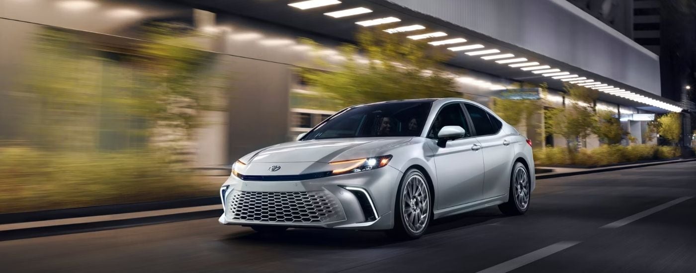 A silver 2025 Toyota Camry Hybrid XSE driving at night.